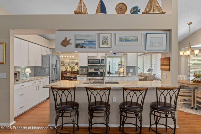 2486 Deer Trail Ln, Spring Hill, FL 34606 - kitchen with stainless steel appliances, a sink, backsplash, white cabinetry, and a chandelier