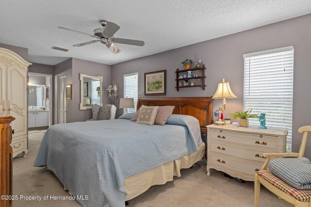 2486 Deer Trail Ln, Spring Hill, FL 34606 - bedroom with light carpet, connected bathroom, a textured ceiling, a closet, and ceiling fan