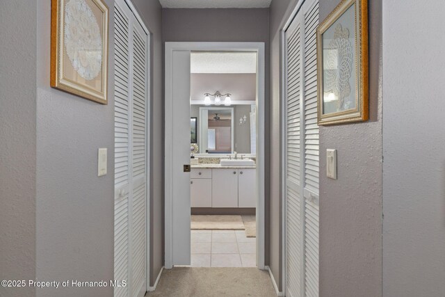 2486 Deer Trail Ln, Spring Hill, FL 34606 - hallway featuring a sink, light carpet, light tile patterned floors, and a textured wall