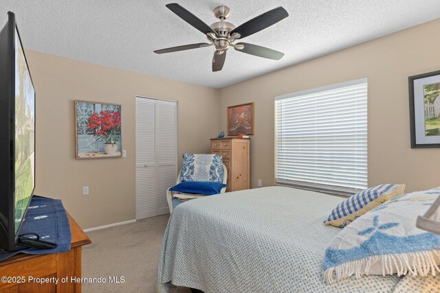 2486 Deer Trail Ln, Spring Hill, FL 34606 - bedroom with carpet floors, a closet, a textured ceiling, a ceiling fan, and baseboards