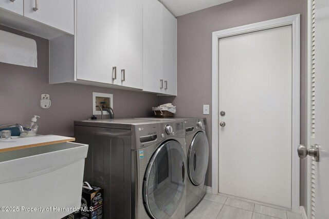 2486 Deer Trail Ln, Spring Hill, FL 34606 - laundry area featuring washer and clothes dryer, cabinet space, and light tile patterned flooring