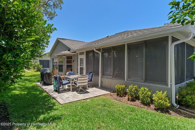 2486 Deer Trail Ln, Spring Hill, FL 34606 - rear view of house with a sunroom, a patio, a lawn, and roof with shingles