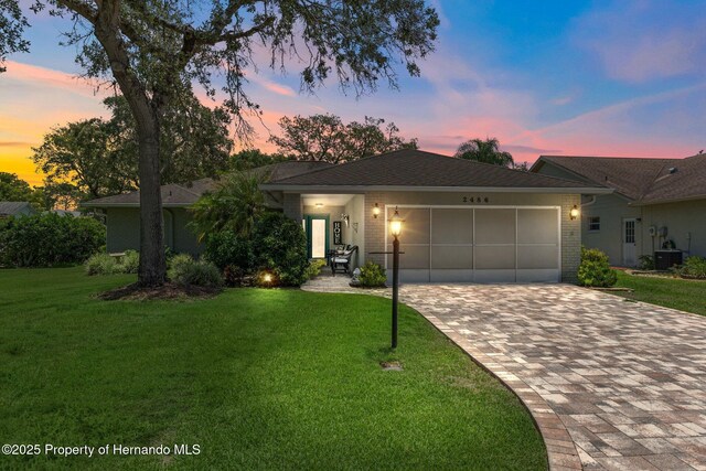 2486 Deer Trail Ln, Spring Hill, FL 34606 - single story home featuring brick siding, an attached garage, decorative driveway, a front lawn, and cooling unit