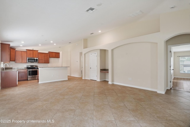 18710 Dobson Dr, Hudson, FL 34667 - unfurnished living room featuring arched walkways, light tile patterned flooring, recessed lighting, baseboards, and a sink
