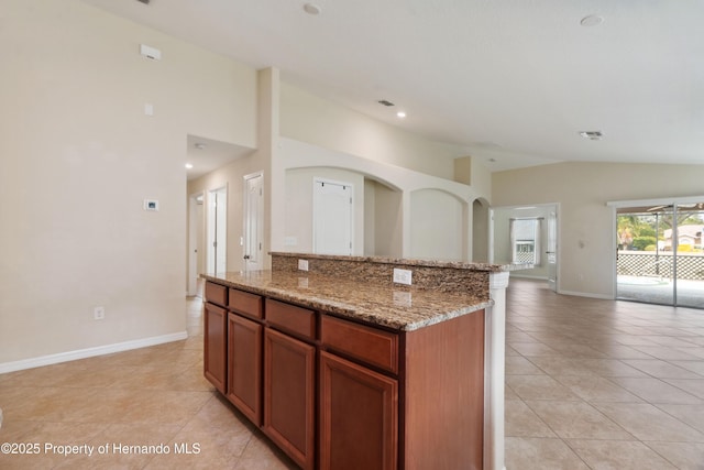 18710 Dobson Dr, Hudson, FL 34667 - kitchen with light tile patterned floors, lofted ceiling, open floor plan, a center island, and light stone counters
