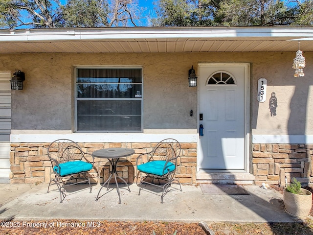 1531 NE 38th St, Ocala, FL 34479 - view of exterior entry with stucco siding, stone siding, and a porch