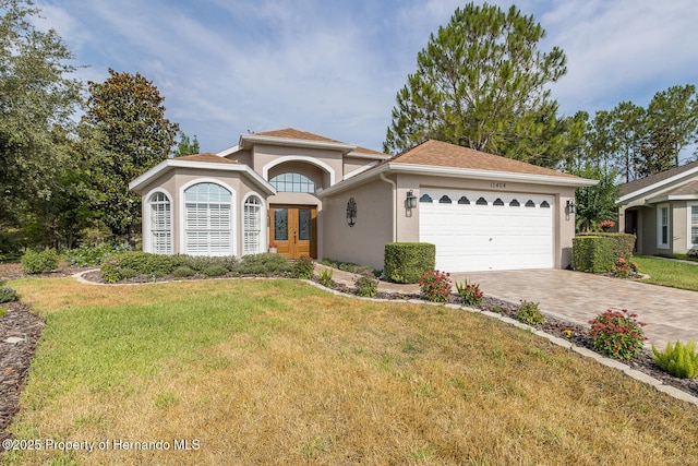 11404 Inman Ct, Spring Hill, FL 34609 - mediterranean / spanish house featuring stucco siding, french doors, a garage, driveway, and a front yard