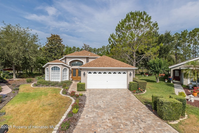 11404 Inman Ct, Spring Hill, FL 34609 - view of front of house featuring stucco siding, a front lawn, decorative driveway, french doors, and a garage