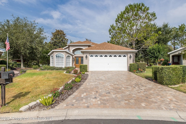11404 Inman Ct, Spring Hill, FL 34609 - view of front of home with a front lawn, stucco siding, a garage, and driveway