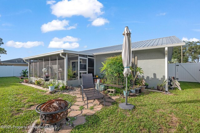 11226 Murraysville Dr, Spring Hill, FL 34609 - back of house with an outdoor fire pit, a sunroom, a gate, metal roof, and stucco siding