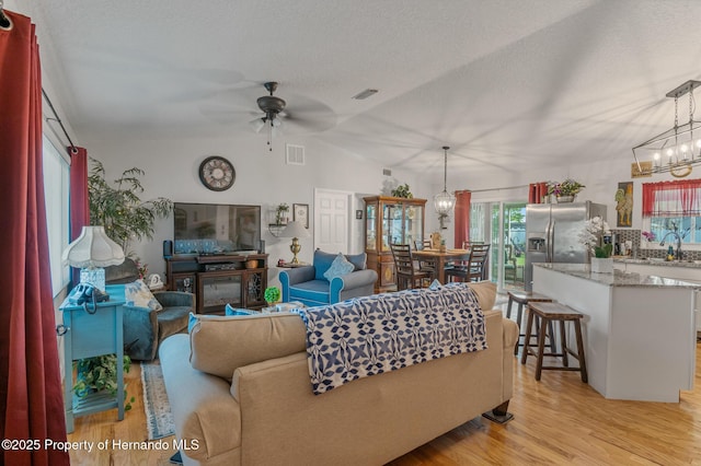 11226 Murraysville Dr, Spring Hill, FL 34609 - living room featuring ceiling fan, light wood-type flooring, a textured ceiling, a chandelier, and vaulted ceiling