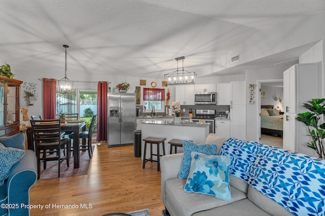 11226 Murraysville Dr, Spring Hill, FL 34609 - living room featuring a chandelier, light wood-type flooring, and a textured ceiling