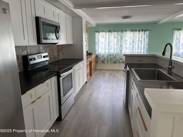 12325 Fairway Ave, Brooksville, FL 34613 - kitchen featuring appliances with stainless steel finishes, dark countertops, decorative backsplash, light wood-style floors, and white cabinetry