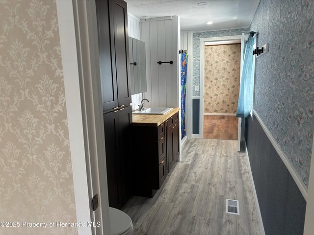 12325 Fairway Ave, Brooksville, FL 34613 - full bathroom featuring wallpapered walls, wood finished floors, and vanity