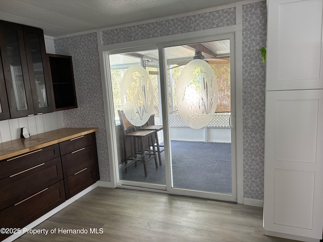 12325 Fairway Ave, Brooksville, FL 34613 - kitchen with wallpapered walls, wood finished floors, crown molding, glass insert cabinets, and dark brown cabinets