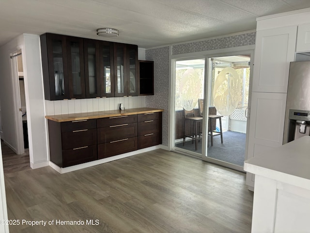 12325 Fairway Ave, Brooksville, FL 34613 - kitchen with wallpapered walls, wood finished floors, dark brown cabinetry, glass insert cabinets, and stainless steel fridge with ice dispenser