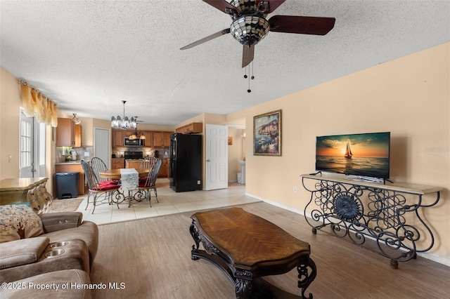 4148 Landover Blvd, Spring Hill, FL 34609 - living room with a ceiling fan, baseboards, a chandelier, a textured ceiling, and light wood-style flooring