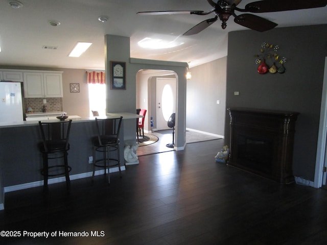 8423 Dickens Ave, Brooksville, FL 34613 - kitchen with arched walkways, freestanding refrigerator, a kitchen breakfast bar, a ceiling fan, and dark wood-type flooring