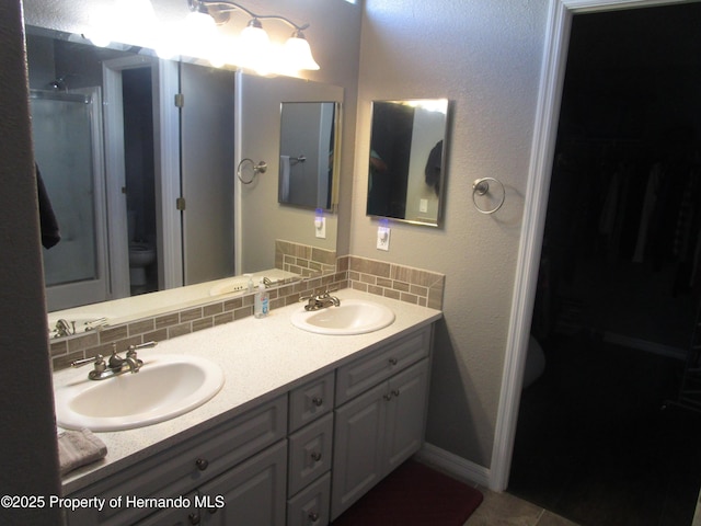 8423 Dickens Ave, Brooksville, FL 34613 - full bath featuring double vanity, a shower with door, decorative backsplash, a walk in closet, and tile patterned flooring