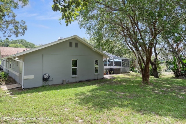 204 Oak Lake Dr, Spring Hill, FL 34608 - back of house featuring a lawn, glass enclosure, and stucco siding