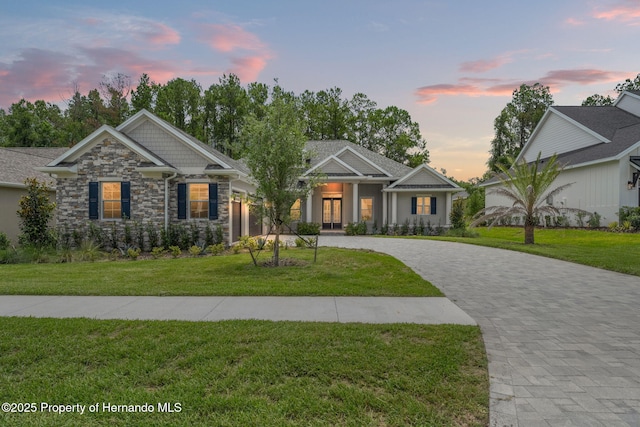 5018 Elm Leaf Dr, Brooksville, FL 34601 - craftsman-style house with curved driveway, stone siding, a front lawn, and french doors