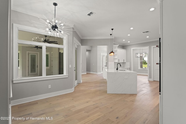 5018 Elm Leaf Dr, Brooksville, FL 34601 - kitchen with crown molding, a chandelier, white cabinetry, light wood-type flooring, and recessed lighting