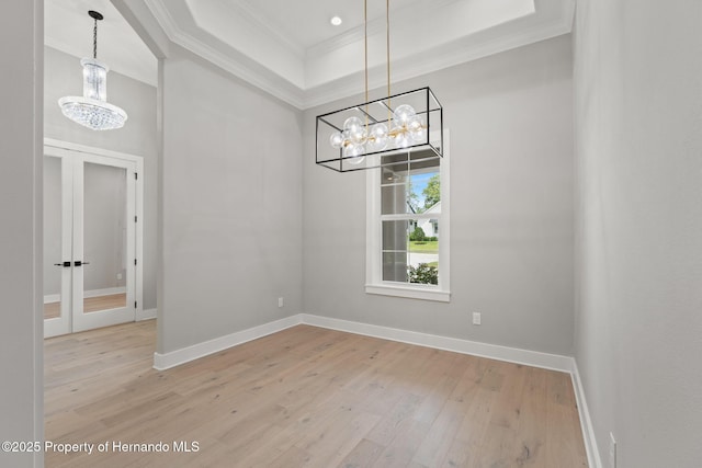 5018 Elm Leaf Dr, Brooksville, FL 34601 - unfurnished dining area featuring crown molding, a chandelier, light wood finished floors, a raised ceiling, and french doors
