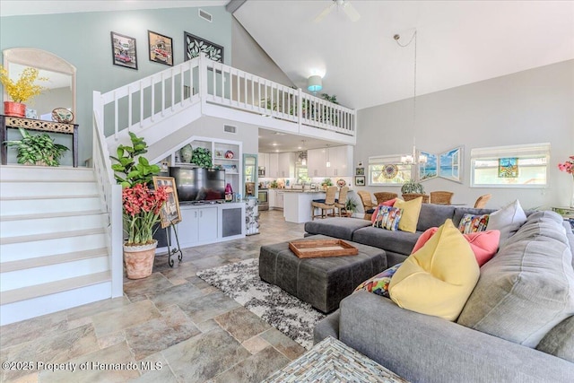 5233 Tuscawilla Dr, Weeki Wachee, FL 34607 - living area with high vaulted ceiling, stone finish flooring, stairway, a chandelier, and ceiling fan