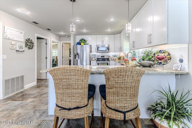 5233 Tuscawilla Dr, Weeki Wachee, FL 34607 - kitchen with appliances with stainless steel finishes, light stone counters, a peninsula, white cabinetry, and recessed lighting