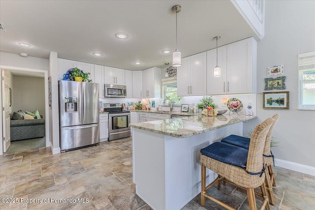 5233 Tuscawilla Dr, Weeki Wachee, FL 34607 - kitchen featuring appliances with stainless steel finishes, a peninsula, stone finish flooring, light stone counters, and recessed lighting