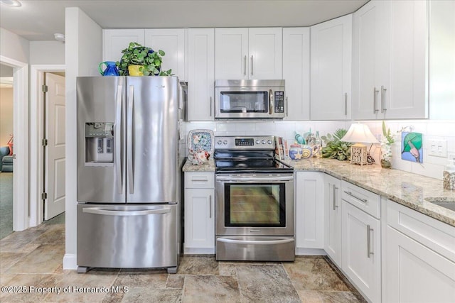 5233 Tuscawilla Dr, Weeki Wachee, FL 34607 - kitchen featuring stainless steel appliances, white cabinets, decorative backsplash, light stone countertops, and stone finish flooring