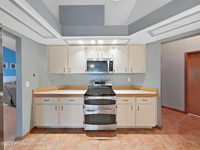 13094 Huntington Woods Ave, Spring Hill, FL 34609 - kitchen featuring stainless steel appliances, light countertops, cream cabinets, and a tray ceiling