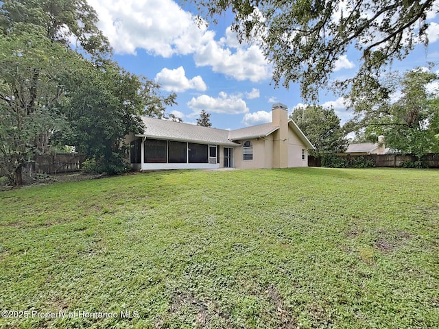 13094 Huntington Woods Ave, Spring Hill, FL 34609 - back of house featuring a chimney, a fenced backyard, and a sunroom