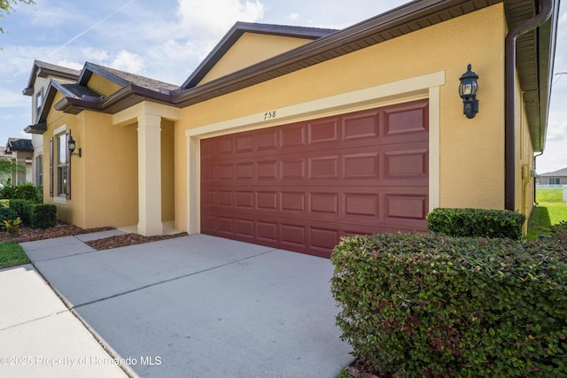 758 Alpine Thistle Dr, Brooksville, FL 34604 - view of home's exterior with stucco siding, an attached garage, and concrete driveway