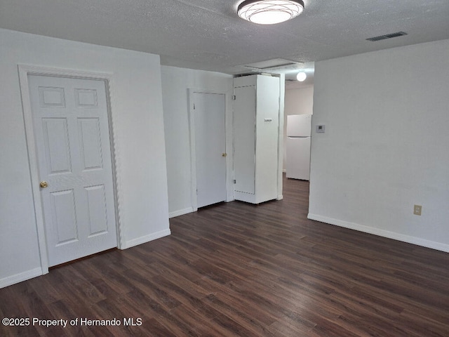 7344 California St, Brooksville, FL 34601 - unfurnished bedroom featuring freestanding refrigerator, dark wood finished floors, a textured ceiling, and a closet