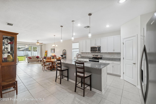 1098 Old Windsor Way, Spring Hill, FL 34609 - kitchen featuring appliances with stainless steel finishes, backsplash, light tile patterned floors, stone counters, and a breakfast bar area