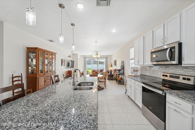 1098 Old Windsor Way, Spring Hill, FL 34609 - kitchen with stainless steel appliances, backsplash, white cabinets, dark stone countertops, and light tile patterned floors