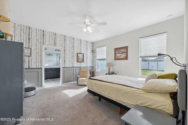 1098 Old Windsor Way, Spring Hill, FL 34609 - bedroom featuring wallpapered walls, wainscoting, carpet flooring, ensuite bath, and a ceiling fan
