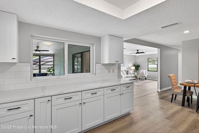 6310 Gainsboro Ave, Spring Hill, FL 34609 - kitchen with ceiling fan, white cabinets, light wood finished floors, a textured ceiling, and backsplash
