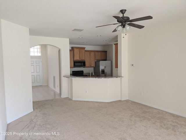 109 Fairmont Dr, Spring Hill, FL 34609 - kitchen featuring appliances with stainless steel finishes, brown cabinets, arched walkways, light carpet, and a ceiling fan