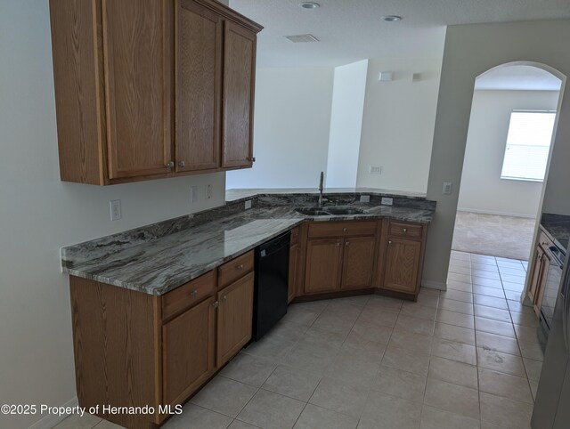 109 Fairmont Dr, Spring Hill, FL 34609 - kitchen featuring black dishwasher, arched walkways, dark stone countertops, brown cabinetry, and light tile patterned floors