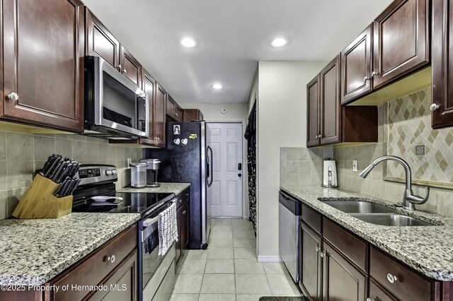 7385 Crestwood Dr, Weeki Wachee, FL 34613 - kitchen with stainless steel appliances, light tile patterned flooring, decorative backsplash, light stone countertops, and recessed lighting
