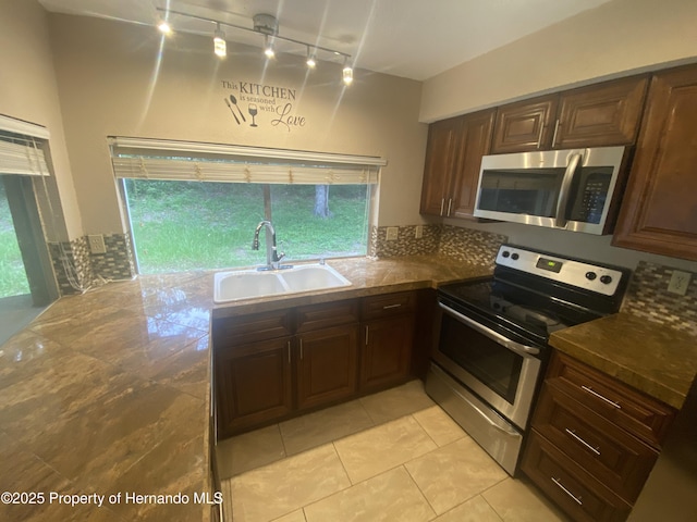 1392 Piper Rd, Spring Hill, FL 34606 - kitchen with stainless steel appliances, rail lighting, dark countertops, and light tile patterned floors