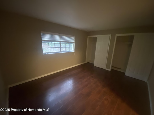1392 Piper Rd, Spring Hill, FL 34606 - unfurnished bedroom with multiple closets and dark wood-style flooring