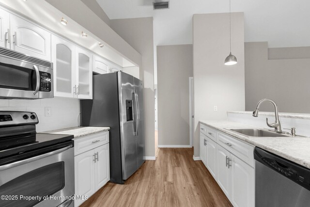 13125 Jessica Dr, Spring Hill, FL 34609 - kitchen featuring stainless steel appliances, light wood finished floors, white cabinetry, and glass insert cabinets