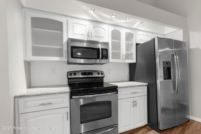 13125 Jessica Dr, Spring Hill, FL 34609 - kitchen with appliances with stainless steel finishes, wood finished floors, decorative backsplash, white cabinets, and glass insert cabinets