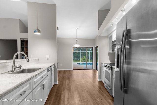 13125 Jessica Dr, Spring Hill, FL 34609 - kitchen featuring stainless steel appliances, wood finished floors, white cabinets, light countertops, and hanging light fixtures