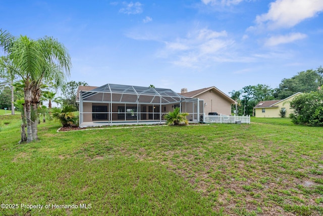 13125 Jessica Dr, Spring Hill, FL 34609 - rear view of property featuring a lawn, glass enclosure, and stucco siding