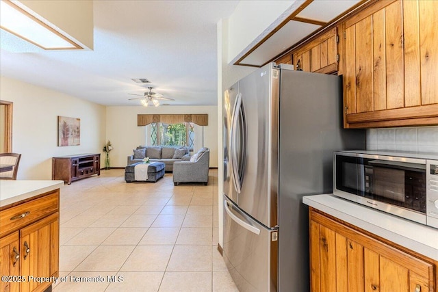 4276 River Birch Dr, Spring Hill, FL 34607 - kitchen with stainless steel appliances, a ceiling fan, light tile patterned floors, light countertops, and brown cabinets