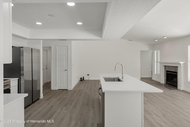 8410 Lakehill Ct, Spring Hill, FL 34608 - kitchen with freestanding refrigerator, light wood-style floors, white cabinetry, light countertops, and an island with sink